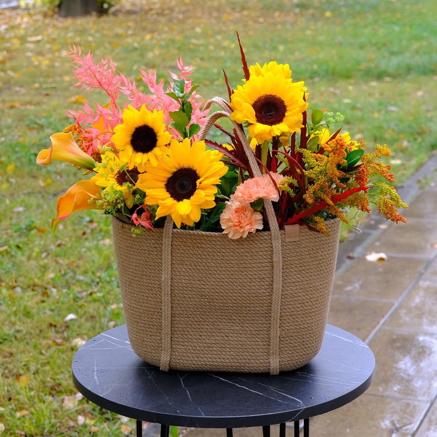 Подсолнухи и каллы в роскошной плетеной сумке