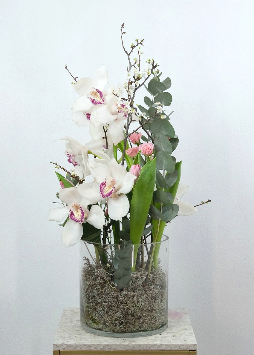 Белая орхидея цимбидиум в стеклянной вазе с эвкалиптом