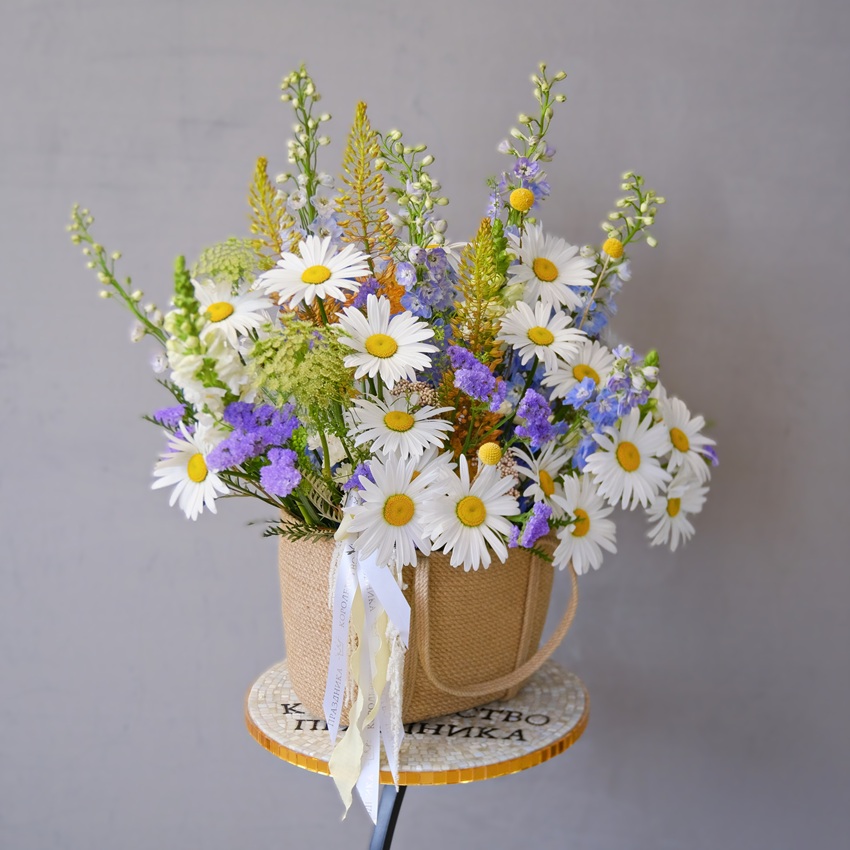 Крупные ромашки и голубой дельфиниум в джутовой сумке "Полевая почта"