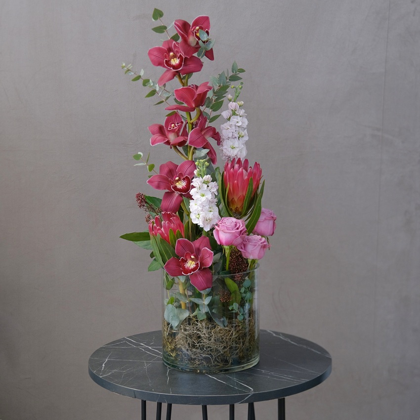 Бордовая орхидея Цимбидиум и протея в стеклянной вазе