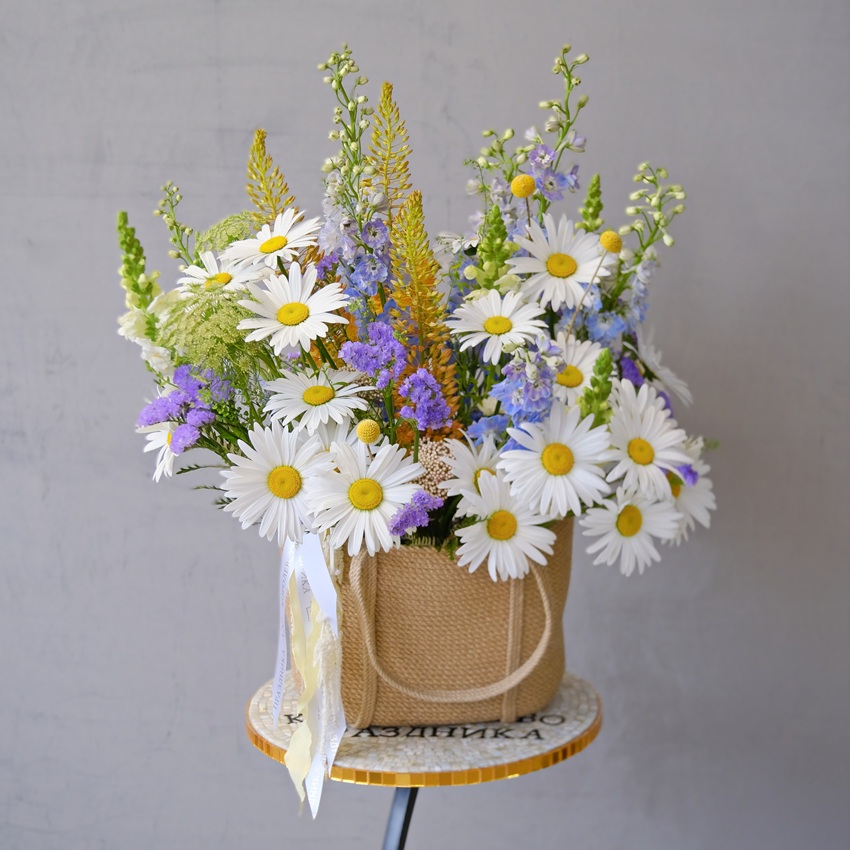 Крупные ромашки и голубой дельфиниум в джутовой сумке "Полевая почта"