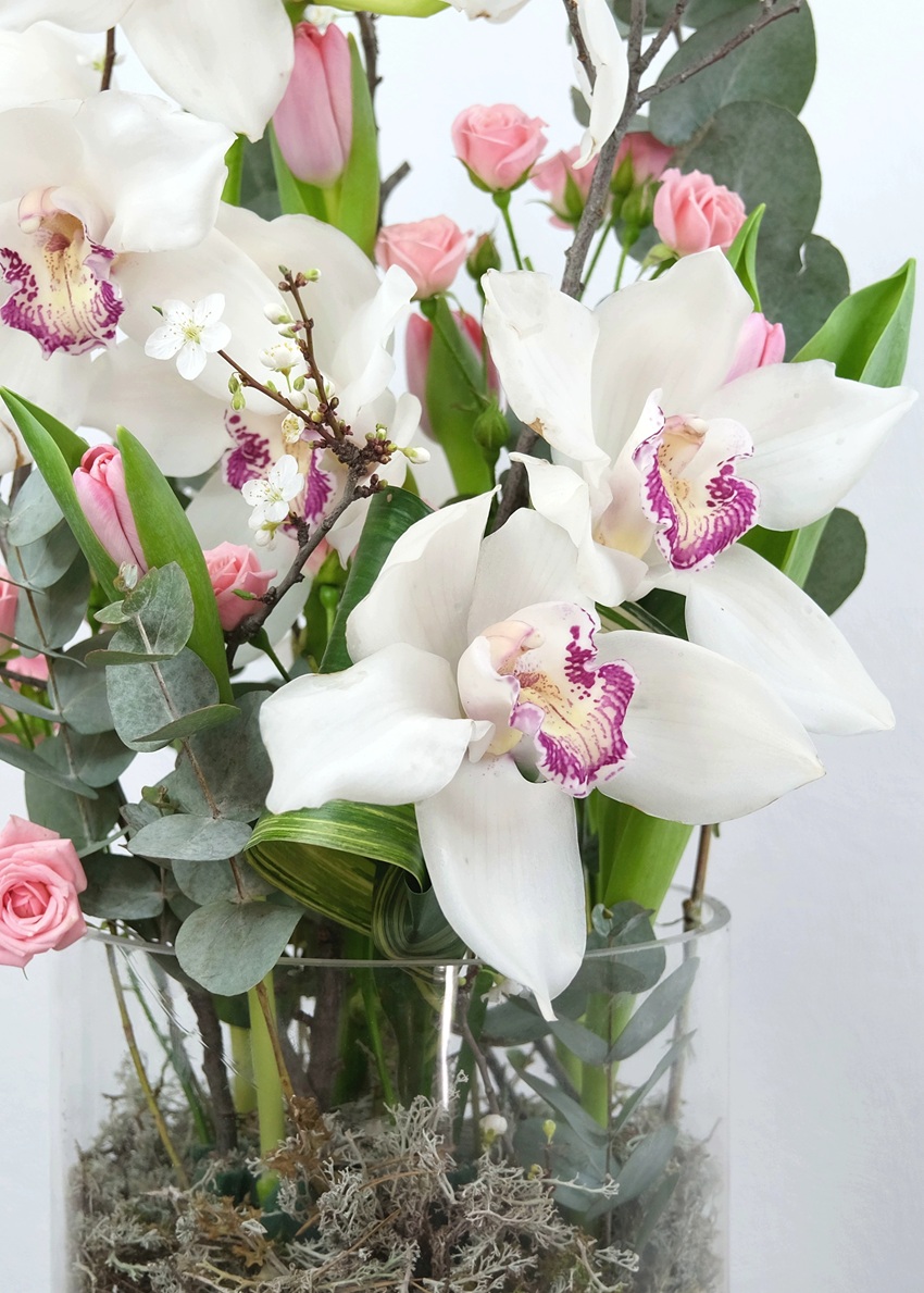 Белая орхидея цимбидиум в стеклянной вазе с эвкалиптом