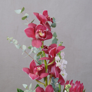 Бордовая орхидея Цимбидиум и протея в стеклянной вазе