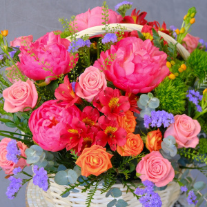 Коралловые пионы и кустовые розы в яркой корзине "Закат над океаном"
