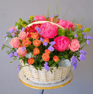 Коралловые пионы и кустовые розы в яркой корзине "Закат над океаном"