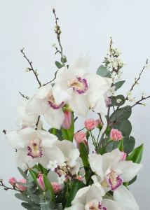 Белая орхидея цимбидиум в стеклянной вазе с эвкалиптом