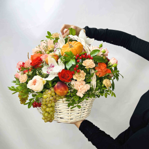 Белые орхидеи и пионовидные розы в осенней корзине с тыковками и фруктами