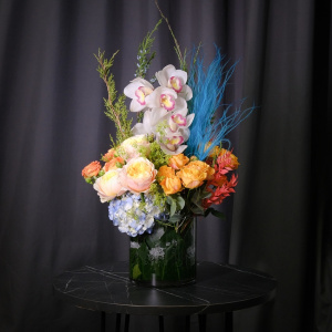 Орхидеи, голубая гортензия и пионовидные розы в стеклянной вазе