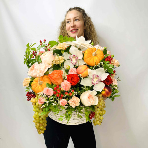 Белые орхидеи и пионовидные розы в осенней корзине с тыковками и фруктами