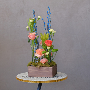 Композиция на Пасху в деревянном ящичке: голубая верба, розы и леукадендрон 