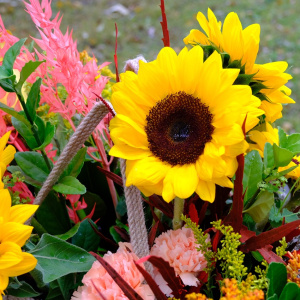 Подсолнухи и каллы в роскошной плетеной сумке