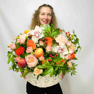 Белые орхидеи и пионовидные розы в осенней корзине с тыковками и фруктами